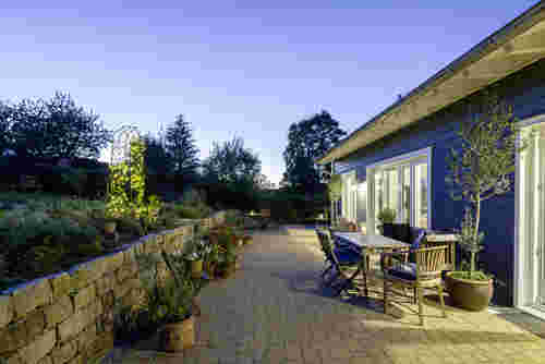 Naturhaus - Terrasse mit Tisch, Topfpflanzen und Garten