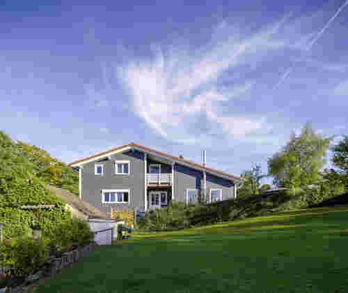 Graues Naturhaus mit Garten unter blauem Himmel